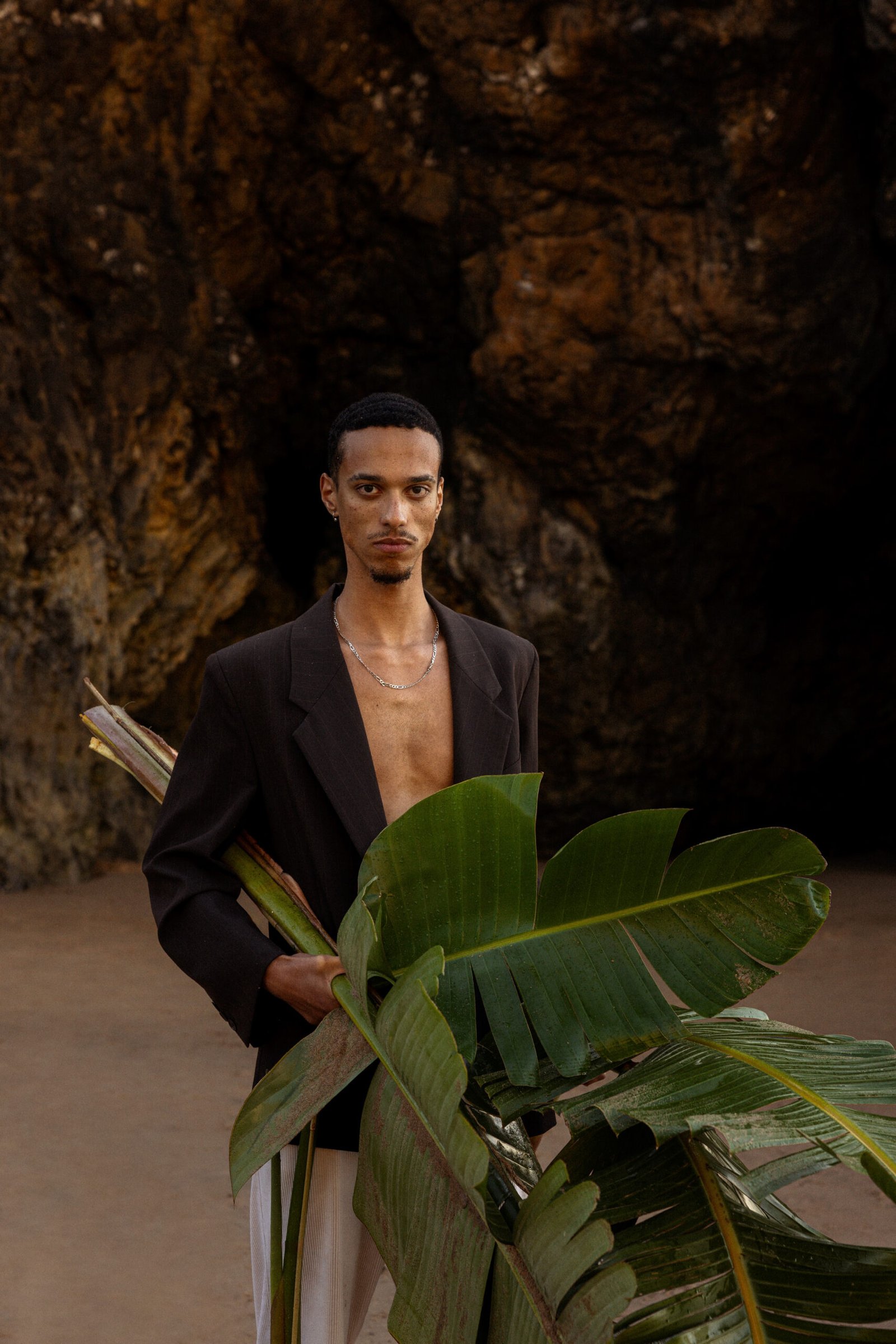 ortrait artistique de Fred en blazer noir avec feuilles tropicales lors d’un voyage photo au Portugal