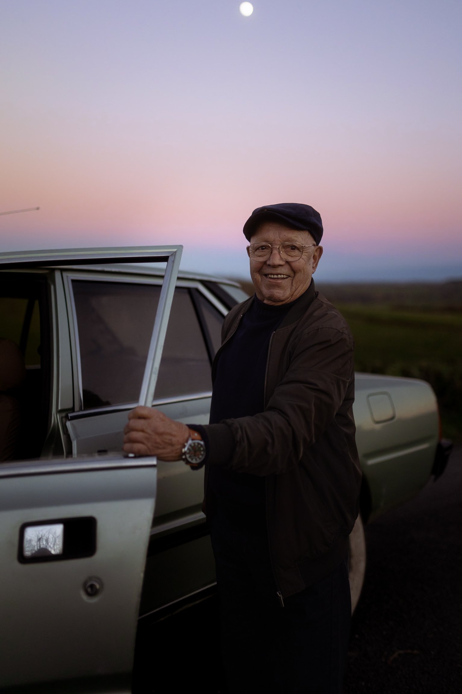 Portrait de Joaquim souriant devant sa voiture au coucher du soleil, photo souvenirs
