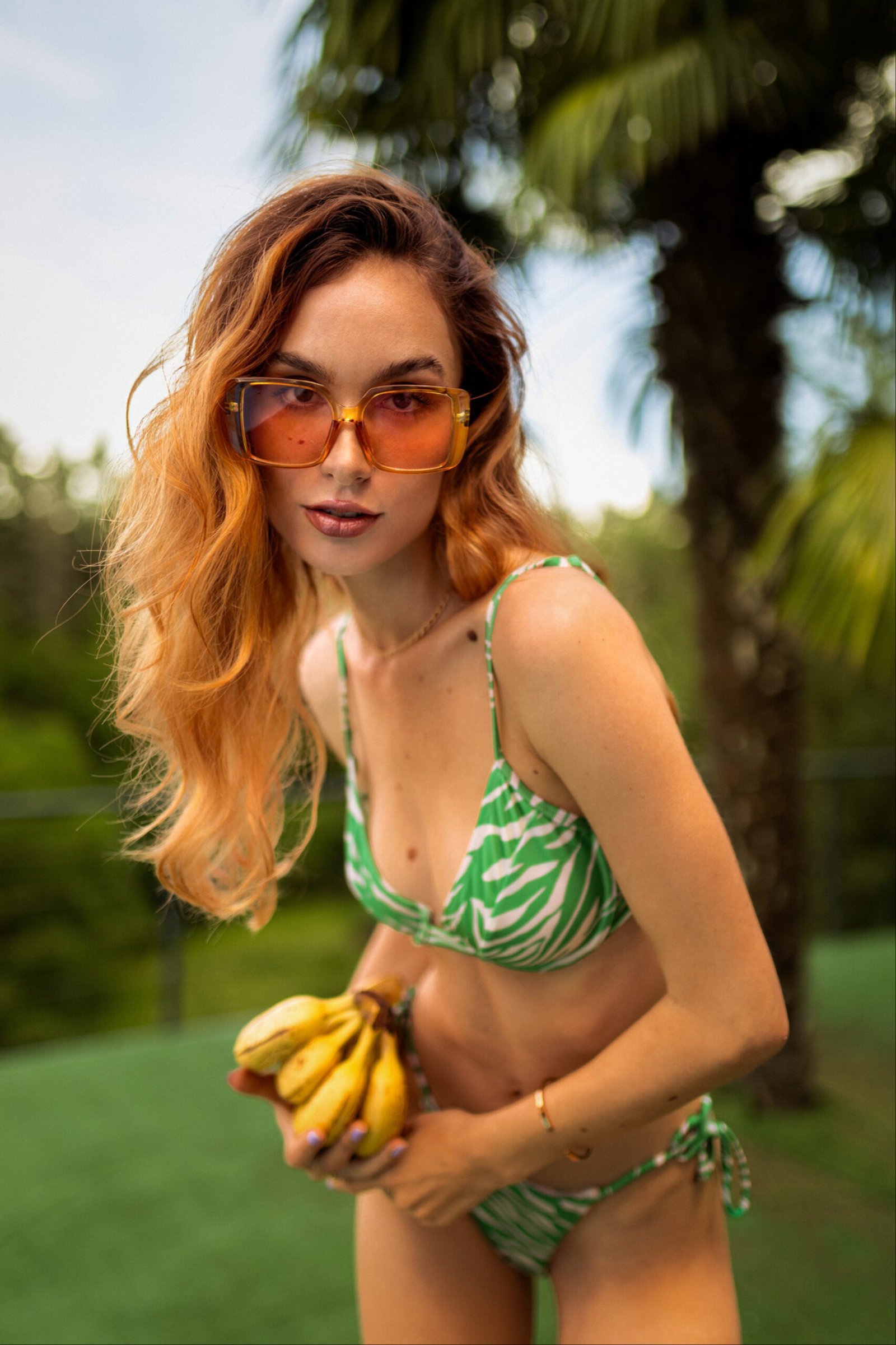 Portrait de Fanny en maillot de bain vert tenant des bananes lors d’un évènement photo dans une villa à Lyon