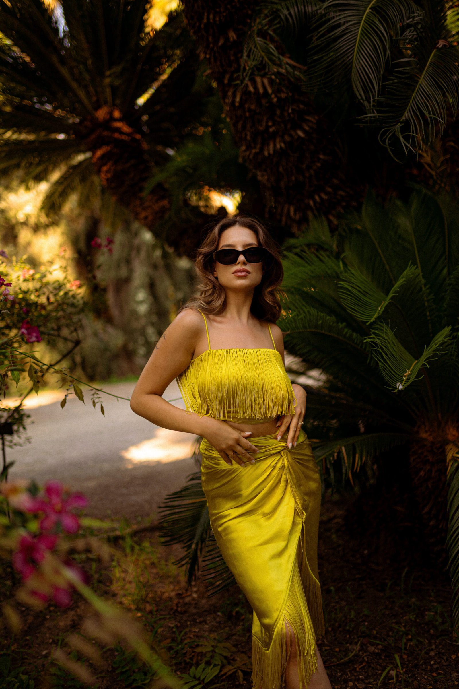 Portrait de Laura en robe jaune lumineuse dans un jardin tropical lors d’un voyage photo en Sicile
