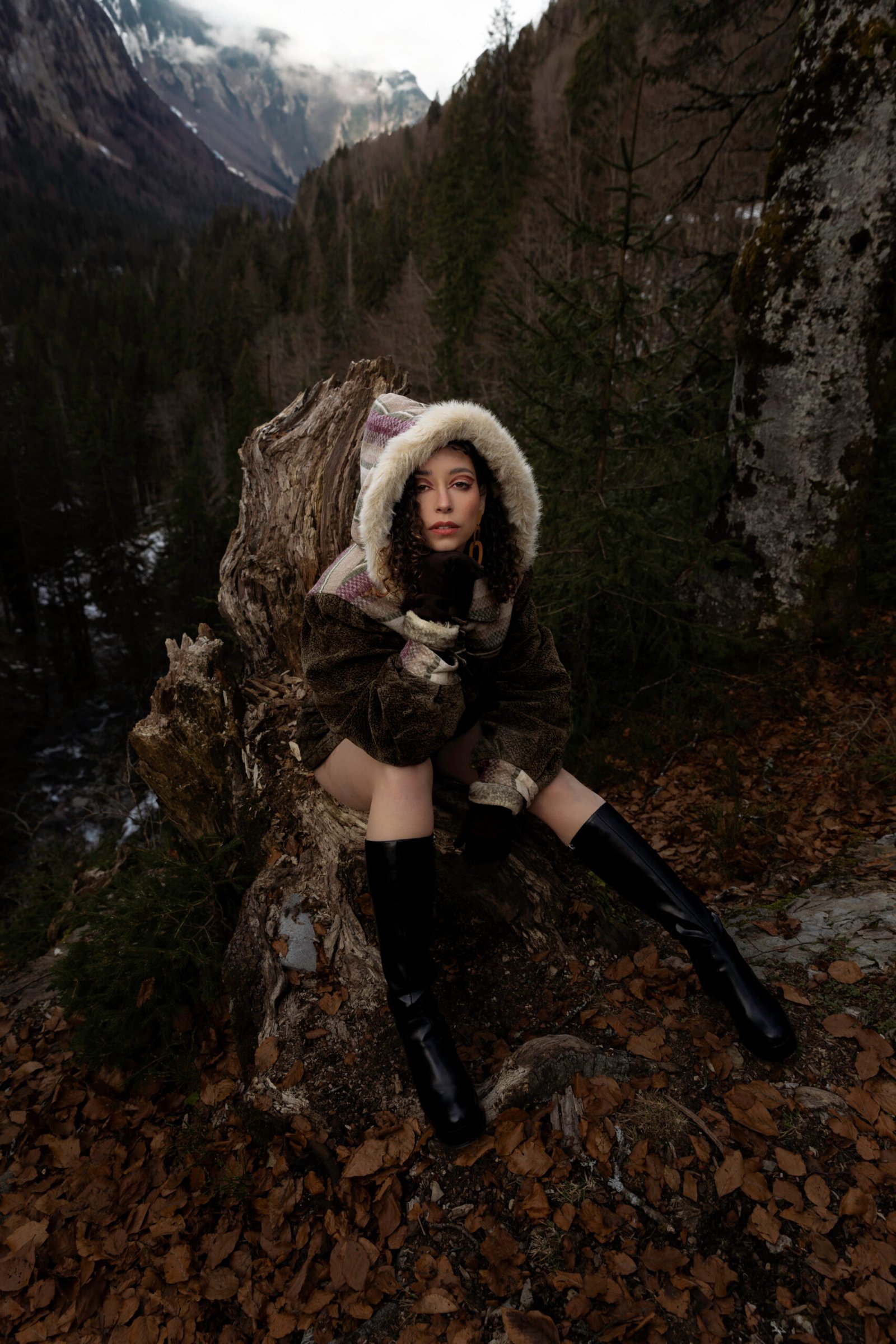 Portrait de Sarah en manteau à capuche dans la forêt lors d’un voyage photo en France pour une marque de vêtements vintage