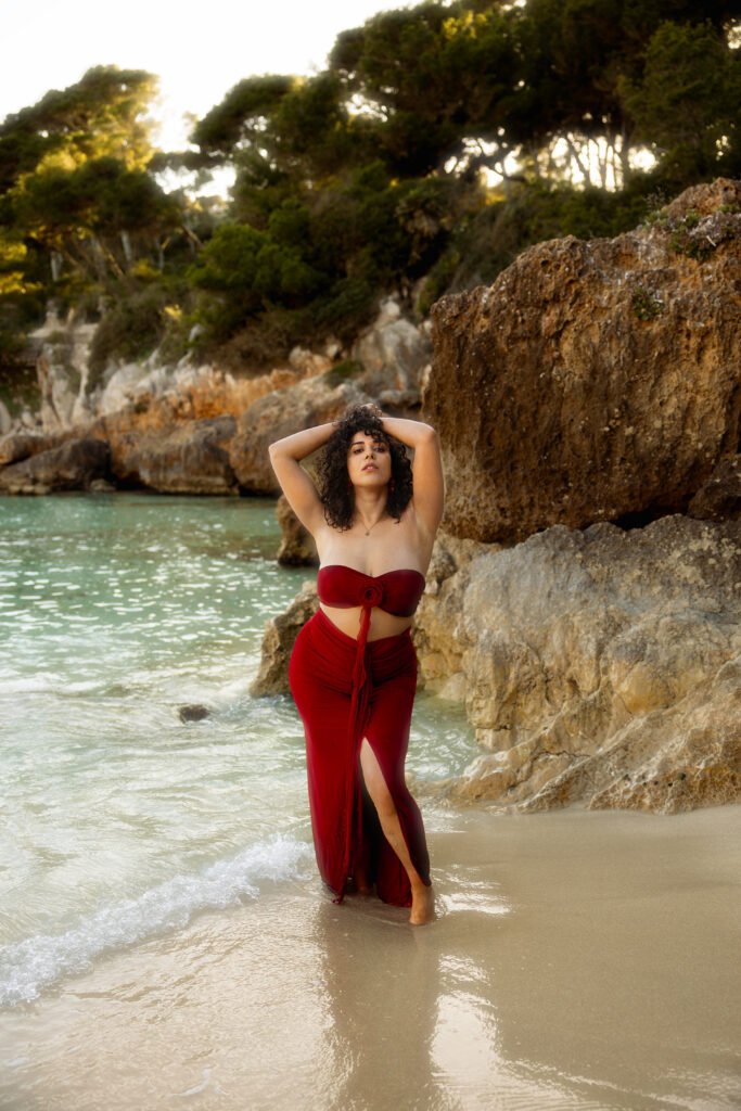 Portrait artistique de Joanna en robe rouge sur une plage à Majorque