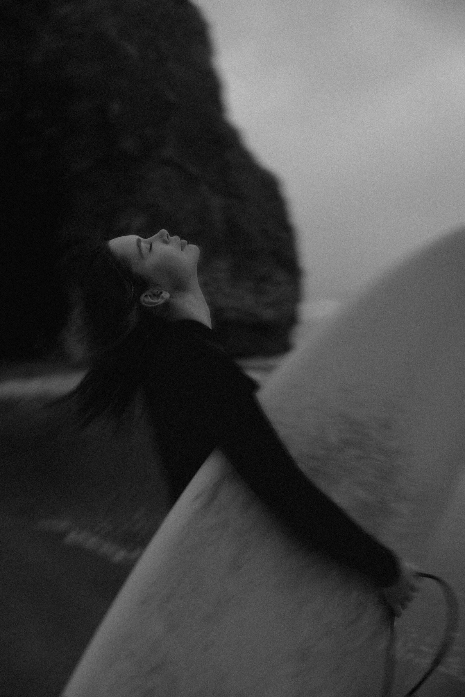 Portrait artistique de Miha avec une planche de surf au Portugal, voyage photo en noir et blanc